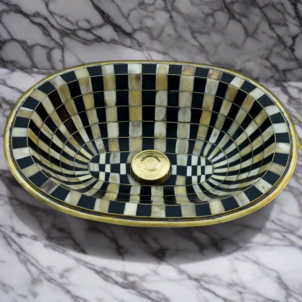 Top view of a handcrafted Moroccan brass bathroom sink with intricate black and white checkerboard pattern