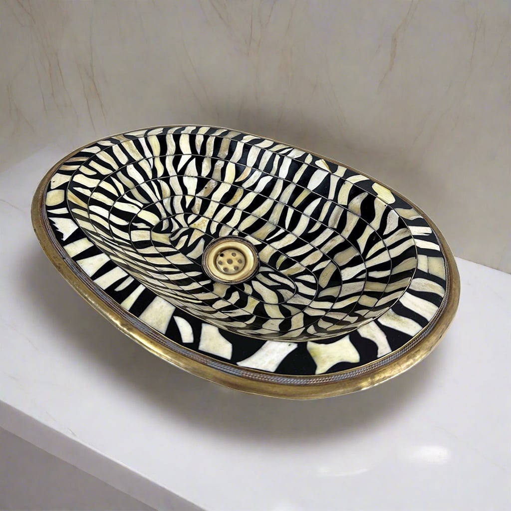 Close-up of the intricate black and white bone inlay pattern on a handcrafted brass bathroom sink from Morocco