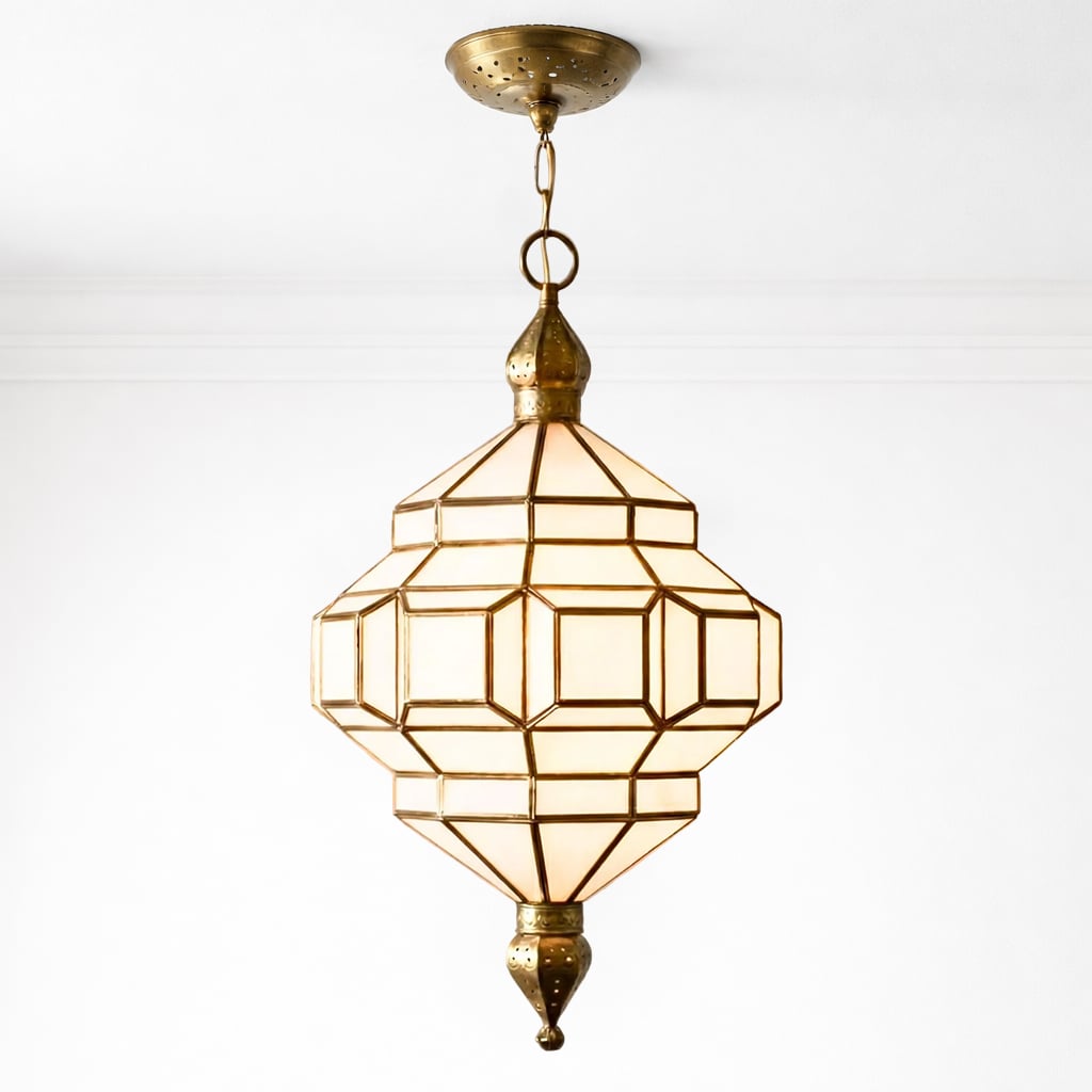 Close-up of a brass Moroccan-inspired pendant light with frosted glass and detailed metalwork, suspended from a white ceiling