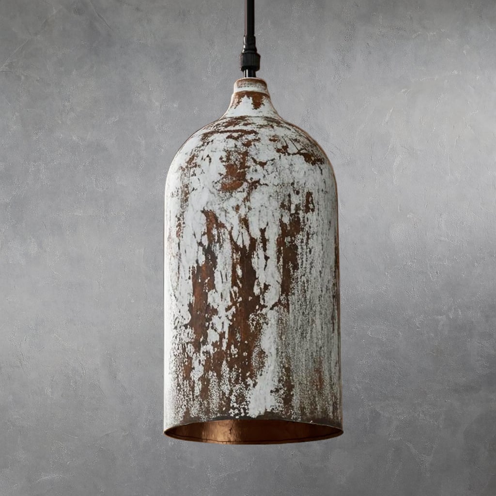 Cylindrical metal pendant lamp with distressed white painted surface and visible brown underlayer, suspended from black cord, interior unlit