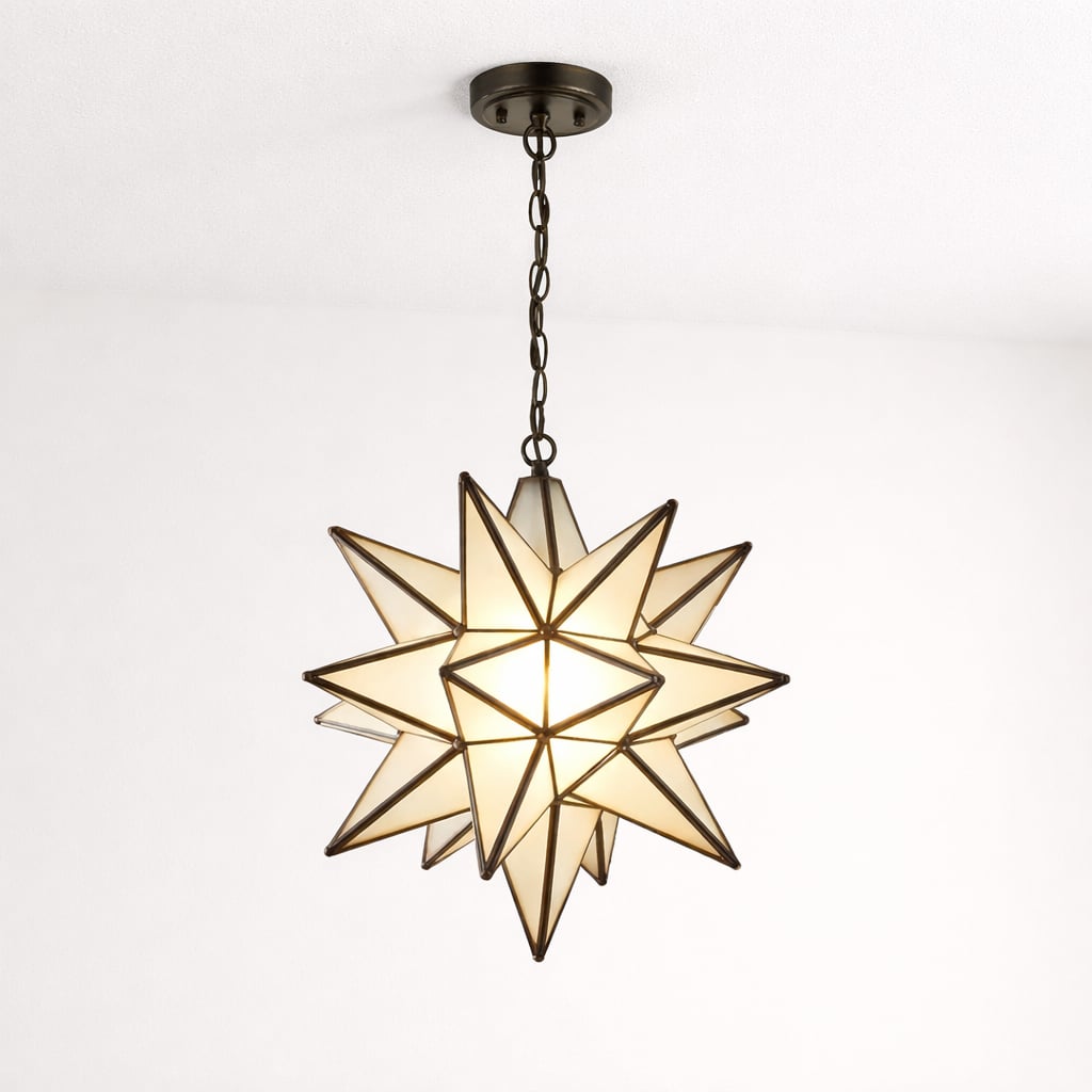 Illuminated Moravian star pendant light with frosted glass panels and black metal frame, suspended by a chain from the ceiling