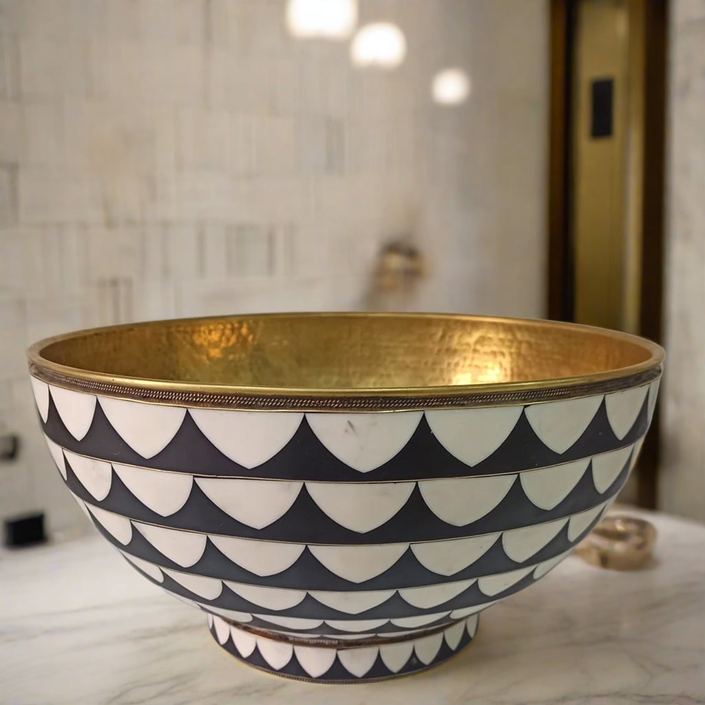Top view of a handcrafted brass bowl sink with black and white Moroccan mosaic accents, showcasing the intricate geometric pattern and hammered brass interior