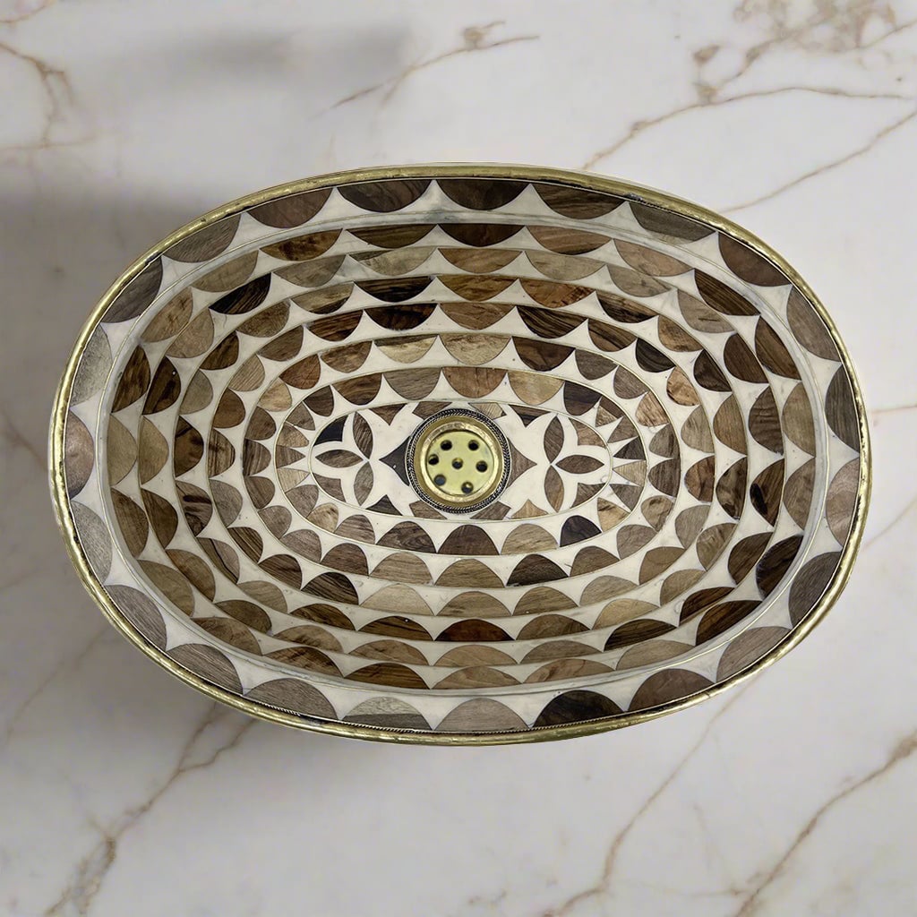 Close-up of a brown and white handcrafted Moroccan brass sink showcasing intricate hand-etched geometric patterns