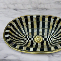 Close-up of the handcrafted brass sink showing detailed resin and bone inlays in a checkerboard pattern