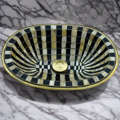 Top view of a handcrafted Moroccan brass bathroom sink with intricate black and white checkerboard pattern