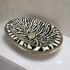 Close-up of the intricate black and white bone inlay pattern on a handcrafted brass bathroom sink from Morocco