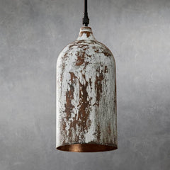 Cylindrical metal pendant lamp with distressed white painted surface and visible brown underlayer, suspended from black cord, interior unlit