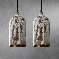 Two cylindrical metal pendant lamps with distressed white painted finish and exposed brown areas, hanging side by side from black cords