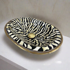 Overhead view of a handcrafted Moroccan brass bathroom sink with intricate black and white bone inlay design
