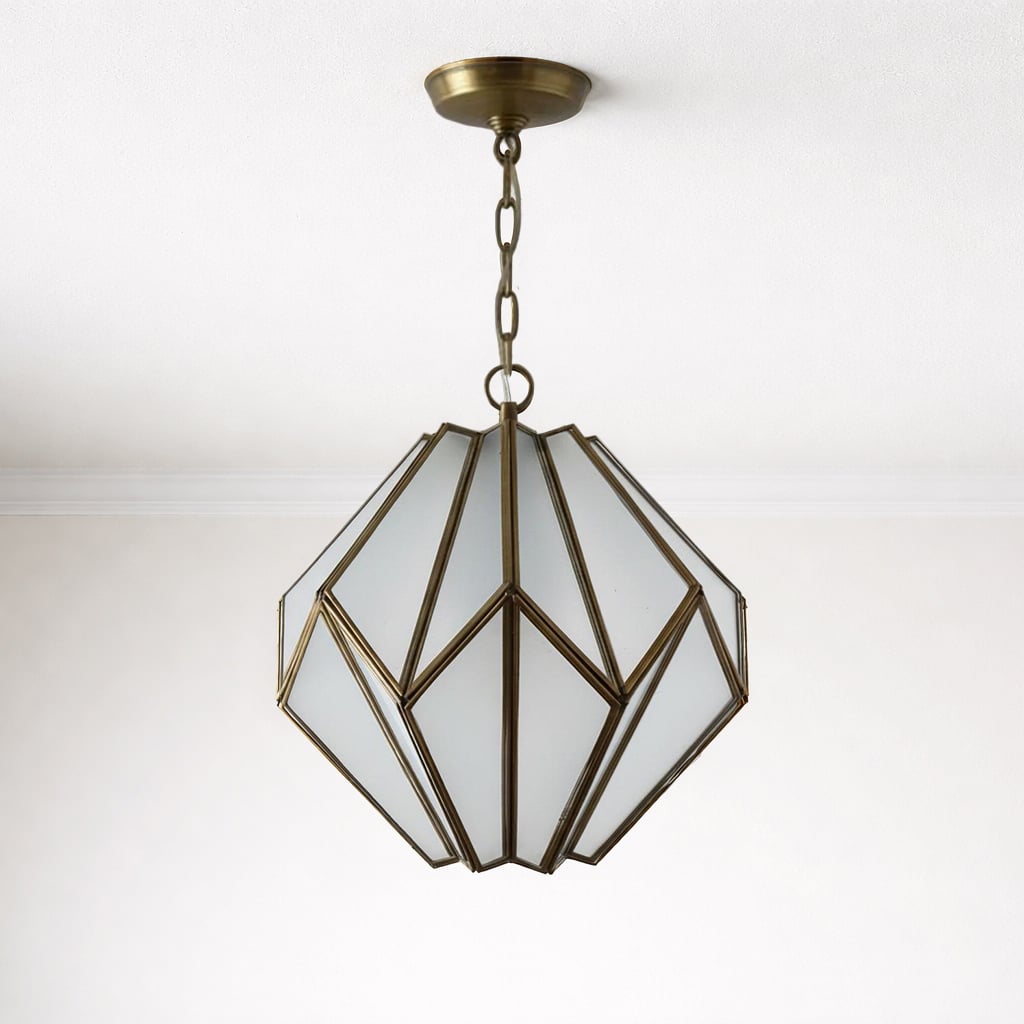 Geometric pendant light with frosted glass panels and an antique brass frame, suspended from a white ceiling by a matching chain