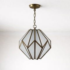 Geometric pendant light with frosted glass panels and an antique brass frame, suspended from a white ceiling by a matching chain