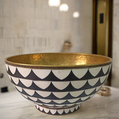 Top view of a handcrafted brass bowl sink with black and white Moroccan mosaic accents, showcasing the intricate geometric pattern and hammered brass interior