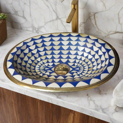 Top view of a handcrafted Moroccan brass bathroom sink with a blue and white geometric pattern, installed on a marble countertop