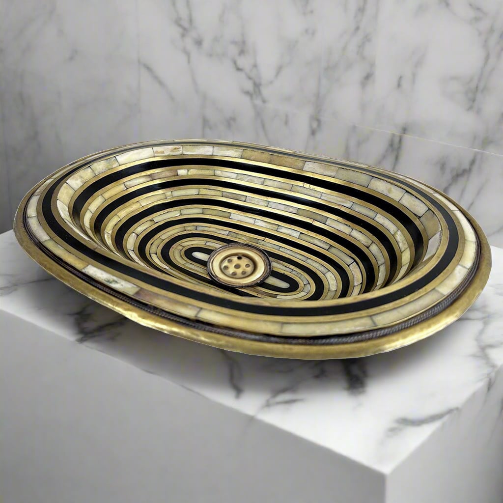 Close-up detail of the resin and bone inlay work on a brass sink, highlighting the craftsmanship and unique pattern