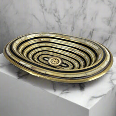 Close-up detail of the resin and bone inlay work on a brass sink, highlighting the craftsmanship and unique pattern