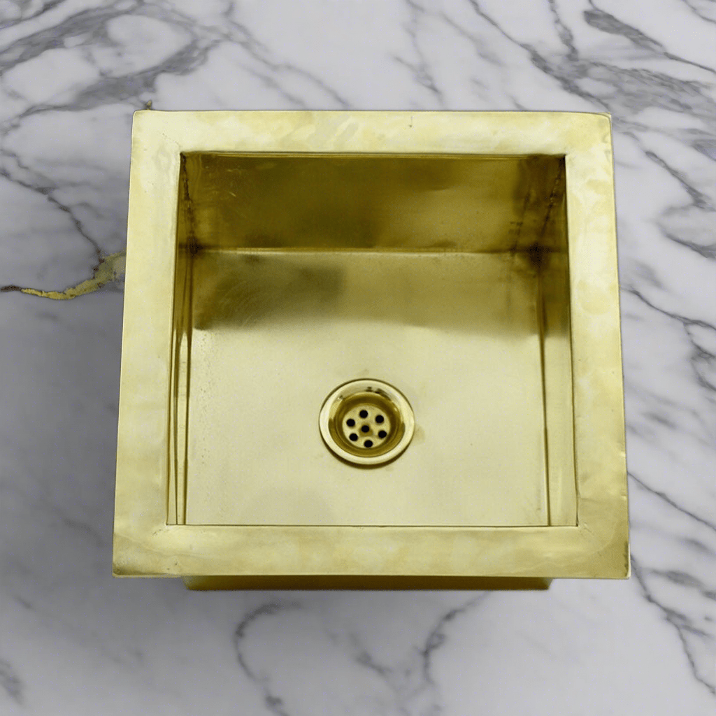 Close-up of a handcrafted brass kitchen sink, highlighting the polished brass material and square design suitable for undermount installation